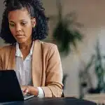 Mulher trabalha em seu laptop, em imagem que ilustra artigo sobre como preencher um recibo.