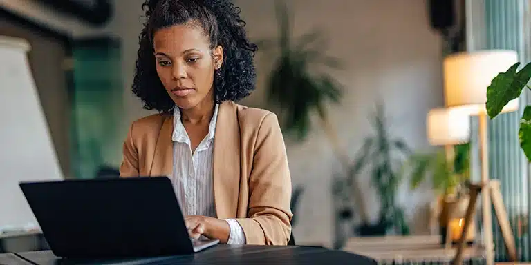 Mulher trabalha em seu laptop, em imagem que ilustra artigo sobre como preencher um recibo.