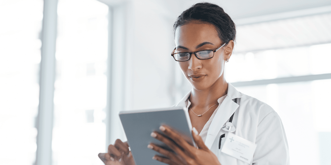 Profissional da área da saúde conferindo a sua agenda de consultas, em um tablet, após entender a diferença entre clínica e consultório de fisioterapia e abrir o seu espaço.