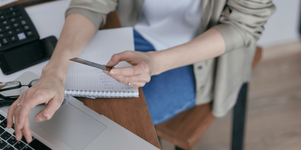 Empreendedora, em seu ao seu notebook, utilizando um cartão, após abrir conta pj com cartão de crédito. | Foto: Mikhail Nilov/Pexels.