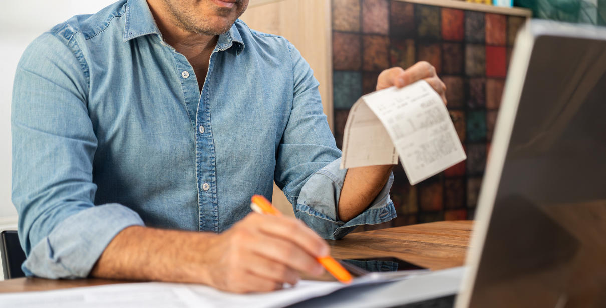homem segurando nota fiscal e fazendo cálculo do capital de giro da empresa