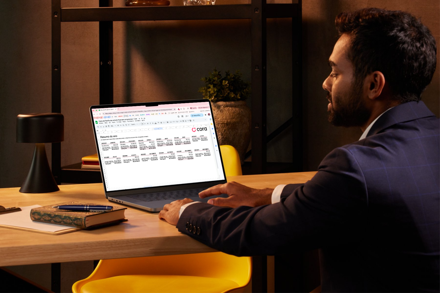 Homem com notebook utilizando a planilha de controle financeiro empresarial da Cora