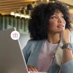 Fotomontagem de mulher pensando, com um computador à sua frente e cercada por ícones financeiros e logotipo da Cora, em imagem que ilustra as diferenças entre a conta PJ da Cora e a de bancos tradicionais