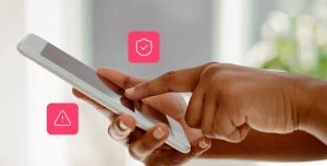 mãos de uma pessoa mexendo num celular, com ícones de segurança e alerta ao redor, em fotomontagem que ilustra artigo sobre golpes e fraudes em boletos bancários