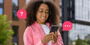 Mulher sorri ao olhar a tela do celular. Ao redor da fotomontagem há ícones de dúvida e de chat, que ajudam a ilustrar artigo sobre marketing conversacional.