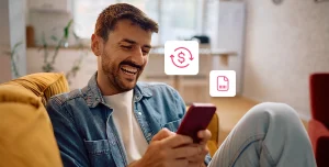 Homem sorri enquanto utiliza um celular, em fotomontagem com ícones financeiros que ilustra artigo sobre taxa de antecipação e CET (Custo Efetivo Total).