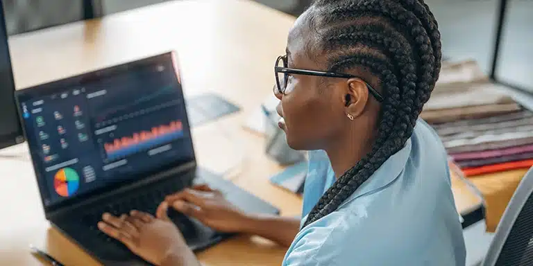 Mulher analisa gráficos em seu laptop, em imagem que ilustra artigo sobre score PJ