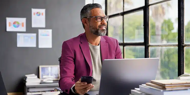 Imagem de Homem pensativo enquanto segura seu smartphone, que ilustra artigo sobre crédito empresarial