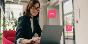 Mulher utiliza laptop. Ao redor, ícones de código de barras e de dinheiro, em fotomontagem sobre emissão de DARF pelo e-CAC da Receita Federal.