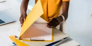 Pessoa manipula pastas e documentos que estão sobre uma mesa, em imagem que ilustra artigo sobre regularização de empresa inativa na Receita Federal do Brasil.