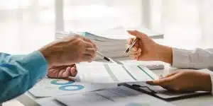 Duas pessoas apontam com canetas para documentos sobre os quais discutem, em imagem que ilustra artigo sobre como preparar seu negócio para uma auditoria fiscal empresarial.
