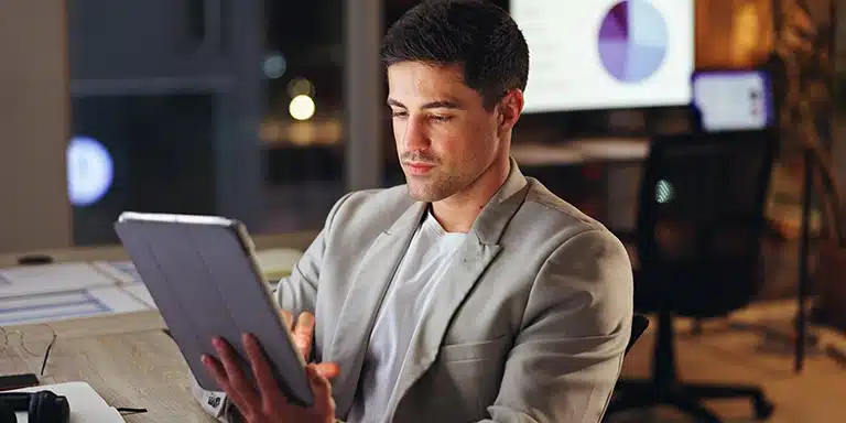 Homem utiliza tablet, em imagem que ilustra artigo que compara os 16 melhores softwares de gestão empresarial.