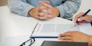 Uma pessoa lê um contrato enquanto a outra espera, em imagem que ilustra artigo sobre os cuidados legais ao antecipar recebíveis.