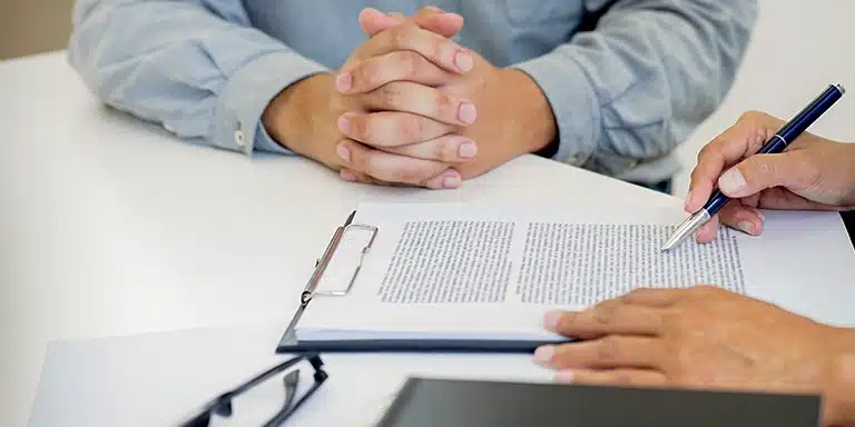 Uma pessoa lê um contrato enquanto a outra espera, em imagem que ilustra artigo sobre os cuidados legais ao antecipar recebíveis.