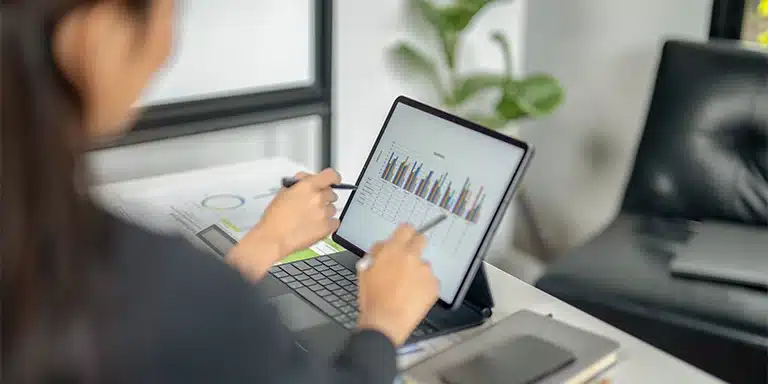 Pessoas analisam gráfico na tela de um tablet, em imagem que ilustra artigo sobre fluxo de caixa projetado.