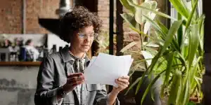 Mulher lê documentos em imagem que ilustra artigo sobre quais impactos fiscais da antecipação de boletos precisam ser avaliados.