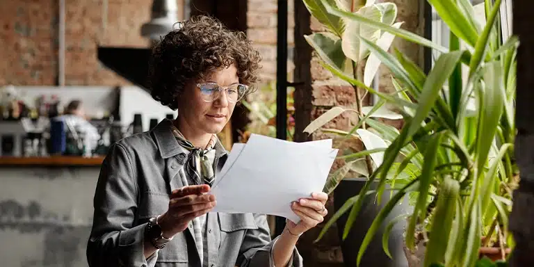 Mulher lê documentos em imagem que ilustra artigo sobre quais impactos fiscais da antecipação de boletos precisam ser avaliados.
