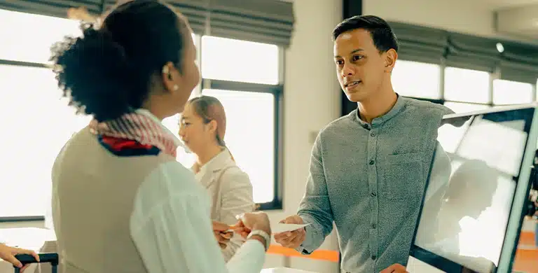 Homem entrega documento para mulher em escritório, em imagem que ilustra artigo sobre abono salarial para empresas