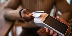 Pessoa efetua pagamento com um cartão em uma maquininha, em imagem que ilustra artigo sobre Cartão PJ para equipes externas: como funciona controle e reembolsos de colaboradores