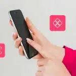 Fotomontagem das mãos de uma pessoa mexendo no smartphone, com ícone de Pix ao redor, para ilustrar artigo sobre tipos de Pix.