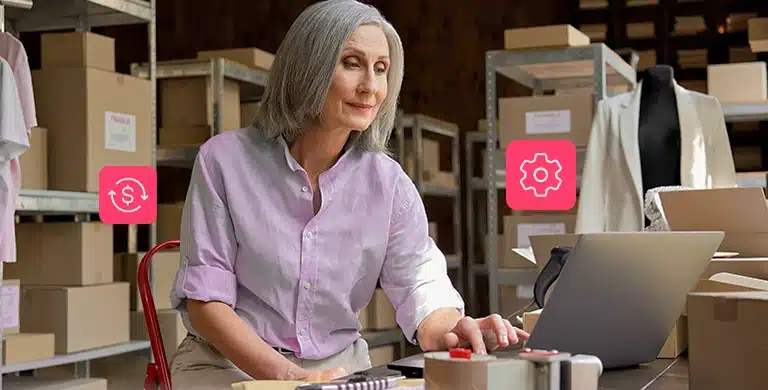 Mulher utiliza um laptop dentro de um estoque, em fotomontagem com ícones de finanças e de engrenagem, que ilustra artigo sobre como automatizar recebimentos na conta PJ.