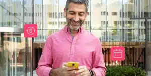Fotomontagem de homem sorrindo ao olhar para a tela de seu celular e com ícones financeiros e de calendário ao redor, para ilustrar artigo sobre limite pré-aprovado para PJ.