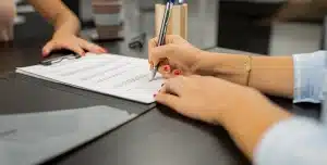 Pessoa assina documento, em imagem que ilustra artigo sobre como fazer um contrato com fornecedores.