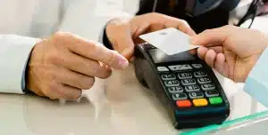 Pessoa efetua pagamento com cartão em uma maquininha, em imagem que ilustra artigo sobre o que deve constar na política de cartão corporativo para equipes pequenas.