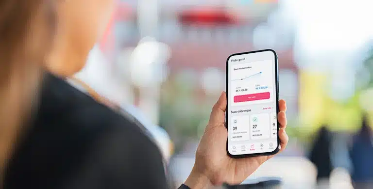 Pessoa segurando um smartphone com o aplicativo da Cora aberto, exibindo dados financeiros na tela, em imagem que ilustra artigo sobre conta PJ da Cora é boa para empresas em crescimento.