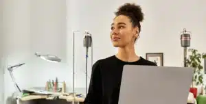 Pessoa em ambiente interno, segurando um notebook aberto e olhando para o lado, em imagem que ilustra artigo sobre se conta PJ online é segura para movimentar valores altos no Brasil.