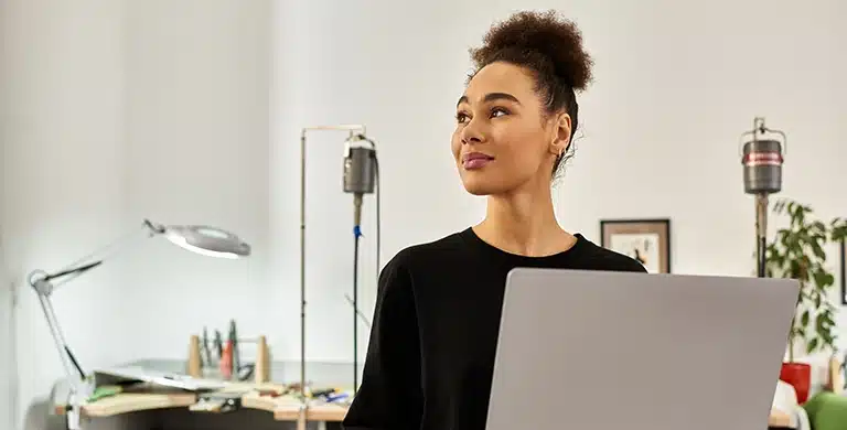 Pessoa em ambiente interno, segurando um notebook aberto e olhando para o lado, em imagem que ilustra artigo sobre se conta PJ online é segura para movimentar valores altos no Brasil.