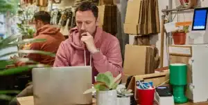 Pessoa sentada à mesa, usando notebook em ambiente interno com objetos de escritório ao redor, em imagem que ilustra artigo sobre vale a pena abrir conta PJ na Cora em 2026.