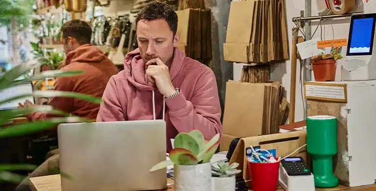 Pessoa sentada à mesa, usando notebook em ambiente interno com objetos de escritório ao redor, em imagem que ilustra artigo sobre vale a pena abrir conta PJ na Cora em 2026.