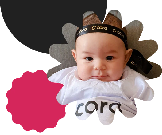 Uma bebê sorrindo olhando para frente, usando uma camiseta branca escrita Cora e uma faixa na cabeça preta com diversas marcas da Cora.
